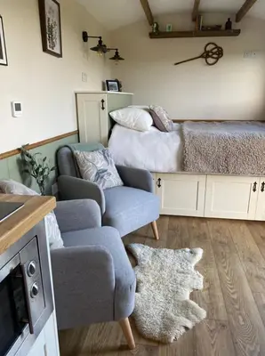 a living room with a couch and a bed at Silver Fern Glamping in Aberystwyth