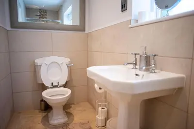 a bathroom with a white toilet and a sink at Country Crabtree Bungalow with large wild garden in Leighton