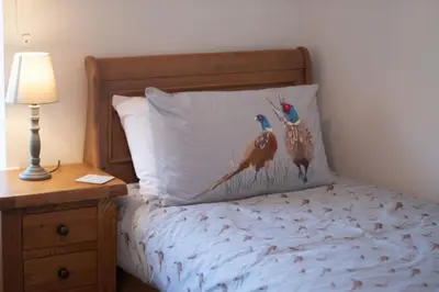 a bedroom with a bed with two birds on the pillow at Country Crabtree Bungalow with large wild garden in Leighton