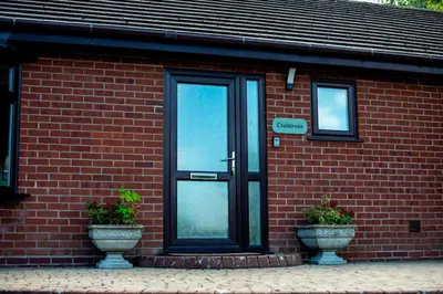 a red brick building with a door and two potted plants at Country Crabtree Bungalow with large wild garden in Leighton