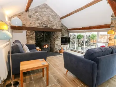 a living room with two blue couches and a stone fireplace at Y Bwthyn in Dyffryn