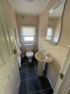 a bathroom with a toilet and a sink and a mirror at Valley View Lodge in Welshpool