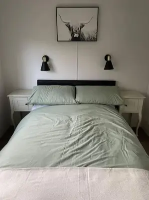 a bed in a bedroom with two tables and a picture of a cow at Valley View Lodge in Welshpool