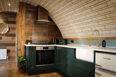 a kitchen with green cabinets and a brick wall at Hedgehogs View in Rhayader