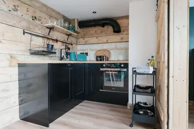 a kitchen with black cabinets and wooden walls at Dyffryn Ceri in Penuwch