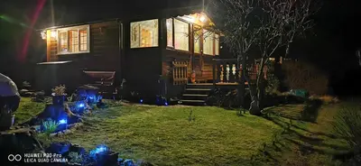 a house with blue lights in the yard at night at Log cabin - free parking garden & pet friendly in Trawsfynydd