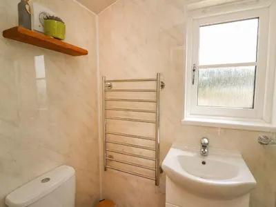 a bathroom with a toilet and a sink and a window at Marches Way in Rhayader
