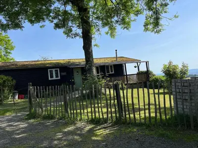 a fence in front of a house with a tree at Wye View Lodge, Hay View Lodges in Hereford