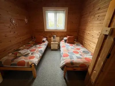 a room with two beds in a log cabin at Wye View Lodge, Hay View Lodges in Hereford
