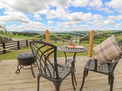 a table and chairs on a wooden deck with a view at Ivy's Way in Rhayader