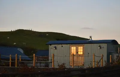 a small building with a window with a hill in the background at Ivy's Way in Rhayader