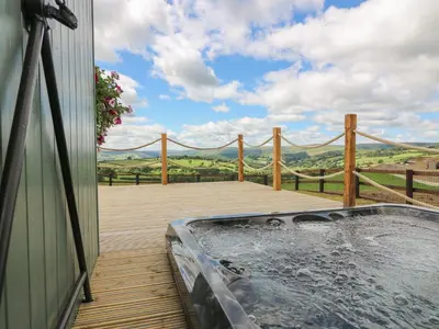 a hot tub on a deck with a fence at Ivy's Way in Rhayader