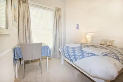 a bedroom with a bed and a desk and a window at Beautiful Aberdovey Seafront Apartment 2 in Aberdyfi