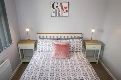 a bedroom with a bed with a pink pillow and two night stands at Riverside Chalet in heart of Lampeter, West Wales in Lampeter
