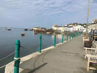 a dock with a chain and boats in the water at Lovely seafront 2 bedroom Apartment 4 in Aberdyfi