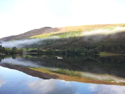 a reflection of a hill in a body of water at Lovely seafront 2 bedroom Apartment 4 in Aberdyfi