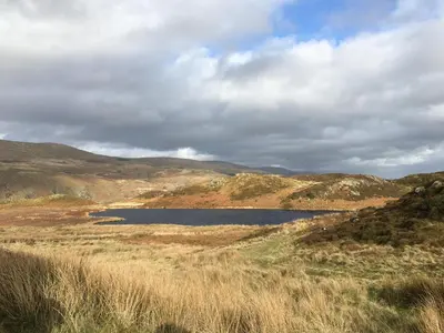 a lake in the middle of a field with hills at Lovely seafront 2 bedroom Apartment 4 in Aberdyfi