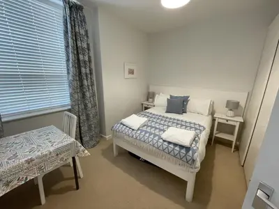 a bedroom with a bed and a table and a window at Lovely seafront 2 bedroom Apartment 4 in Aberdyfi