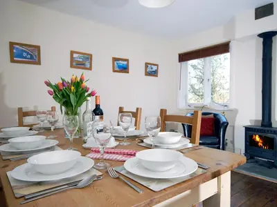 a wooden table with plates and wine glasses and a fireplace at Seafield in New Quay