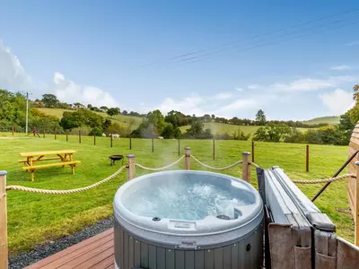 a hot tub on a deck in a field at Chestnut Uk36261 in Llanfair Caereinion