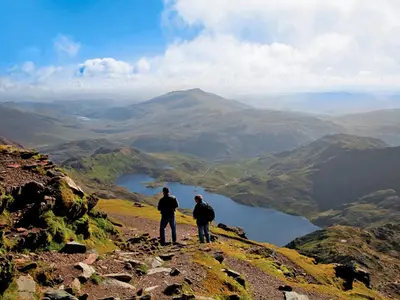 two people standing on top of a mountain overlooking a lake at Fron - Cottage in Mynfford
