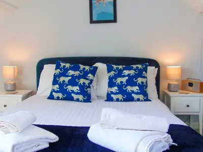 a bed with blue pillows and white towels on it at Y Ty Glas - Cottage in New Quay