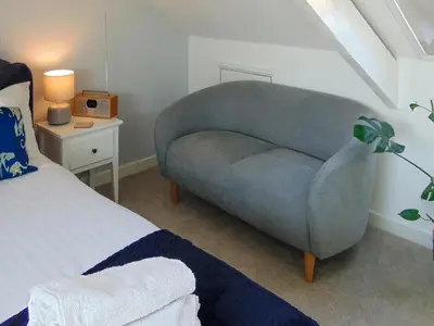a bedroom with a blue chair next to a bed at Y Ty Glas - Cottage in New Quay