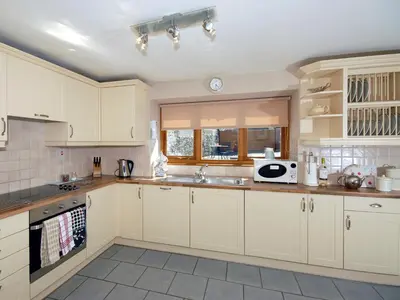 a kitchen with white cabinets and a sink at Cerniw - Cottage in Aberaeron