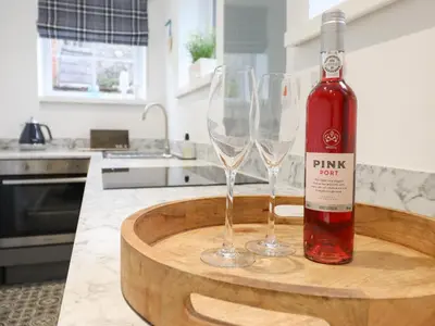 a bottle of wine and two wine glasses on a table at 3 Ivy Court in Dolgellau