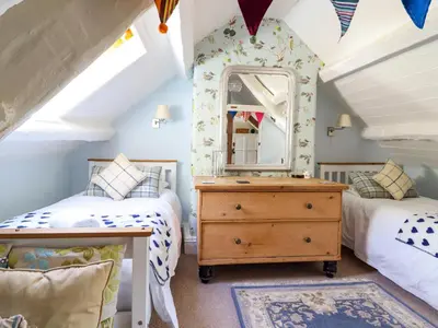 a bedroom with two beds and a dresser with a mirror at Hen Bopty in Fairbourne