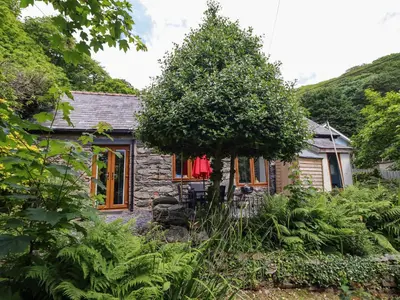 a stone house in the middle of a garden at Hen Bopty in Fairbourne