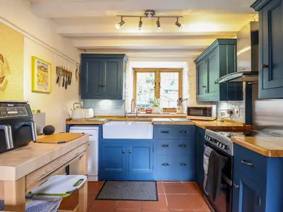 a kitchen with blue cabinets and a sink at Hen Bopty in Fairbourne