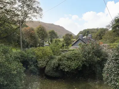 a view of a garden with mountains in the background at Hen Bopty in Fairbourne