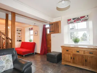 a living room with a red couch and a chair at Ty'n y Clawdd in Dyffryn