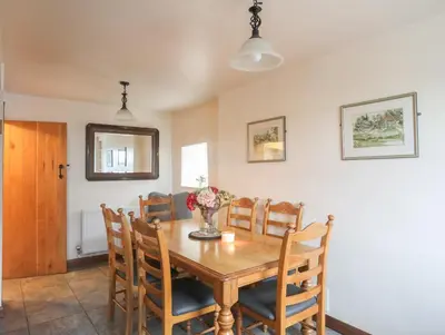 a dining room with a wooden table and chairs at Ty'n y Clawdd in Dyffryn