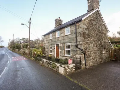 an old stone house on the side of a road at Ty'n y Clawdd in Dyffryn