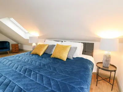 a bedroom with a large blue bed with yellow pillows at Ysgoldy Brynwyre in Llanrhystyd