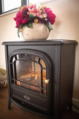 a fireplace with two flowers on top of it at Caban Nant Ddu in Nantmel