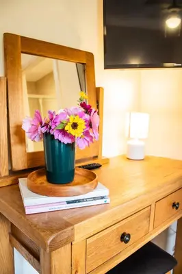 a vase of flowers on a dresser with a mirror at Caban Nant Ddu in Nantmel