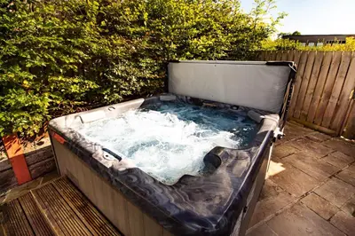 a hot tub sitting on a patio next to a fence at Caban Nant Ddu in Nantmel
