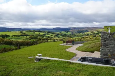 a view of a park with a bench in a field at Foxes View in Rhayader