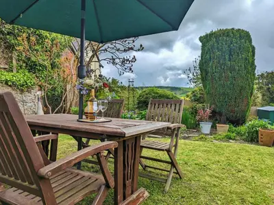 a wooden table with two chairs and an umbrella at Laurgeths House in Bishops Castle