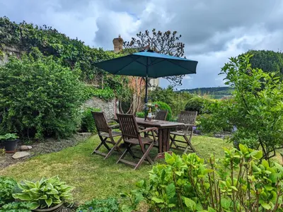 a table and chairs with an umbrella in the grass at Laurgeths House in Bishops Castle