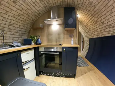 a kitchen with a stove top oven next to a brick wall at Badgers View in Rhayader