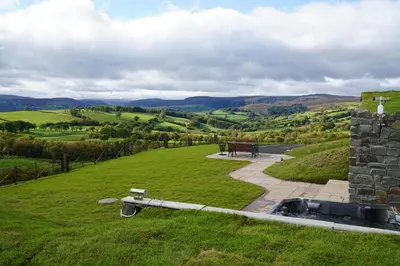 a view of a field with a bench and a hill at Badgers View in Rhayader