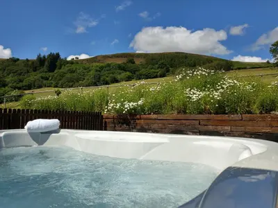 a jacuzzi tub with a view of a field at Seven Stars- hot tub & garden with fabulous views. in Llandrindod Wells