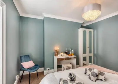 a blue bedroom with a bed and a chair at Jack's House in Tywyn