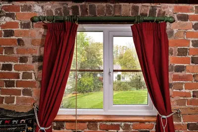 a window with red curtains in a brick wall at Finest Retreats - Great Cantal Granary in Llandrindod Wells