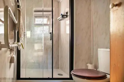a bathroom with a toilet and a glass shower at Finest Retreats - Great Cantal Granary in Llandrindod Wells