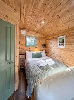 a bedroom with a bed in a wooden cabin at Hwyl in Abbey-Cwmhir